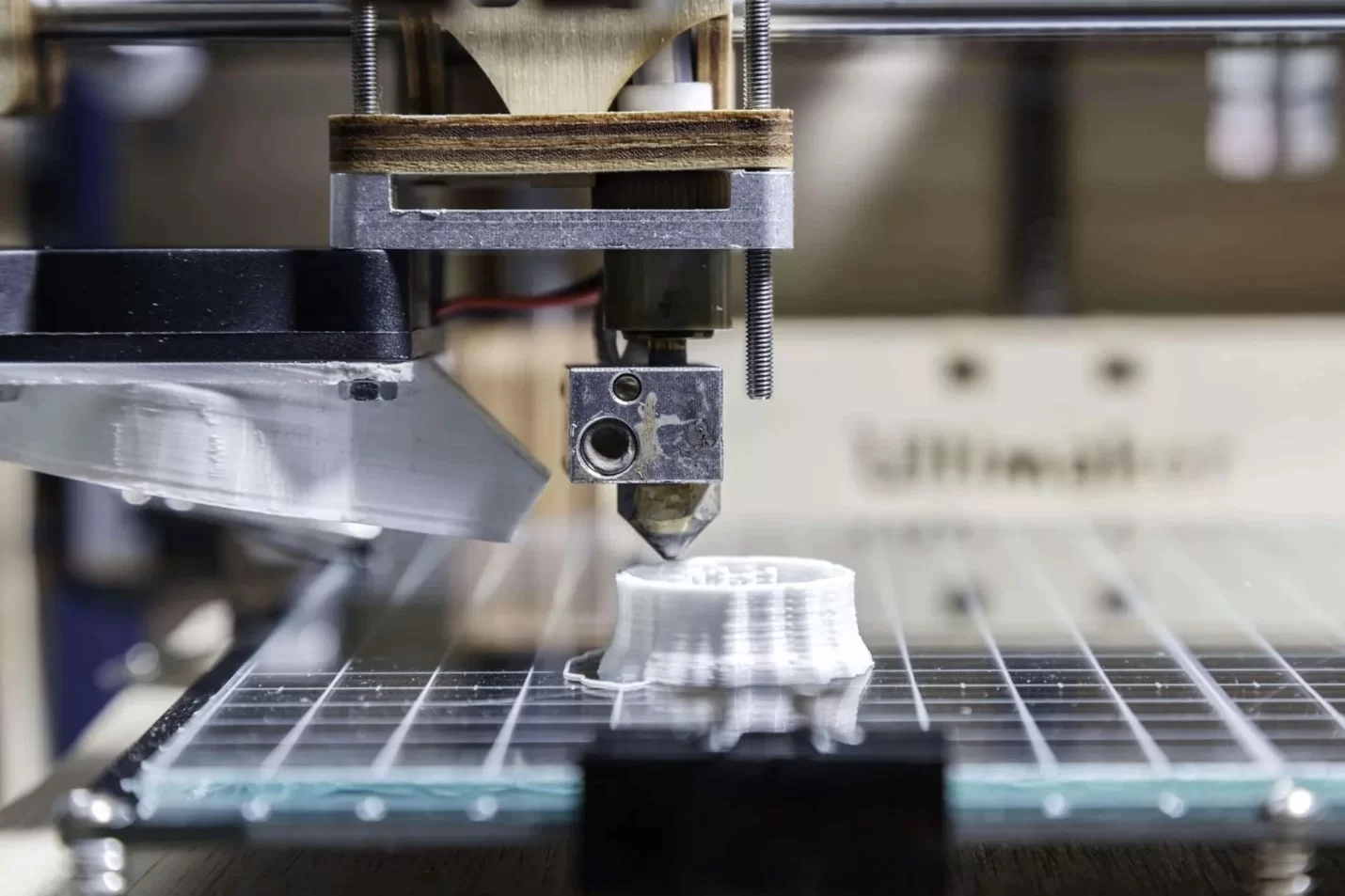 Close-up of a 3D printer creating a white plastic part, showcasing the precision of additive manufacturing technology.